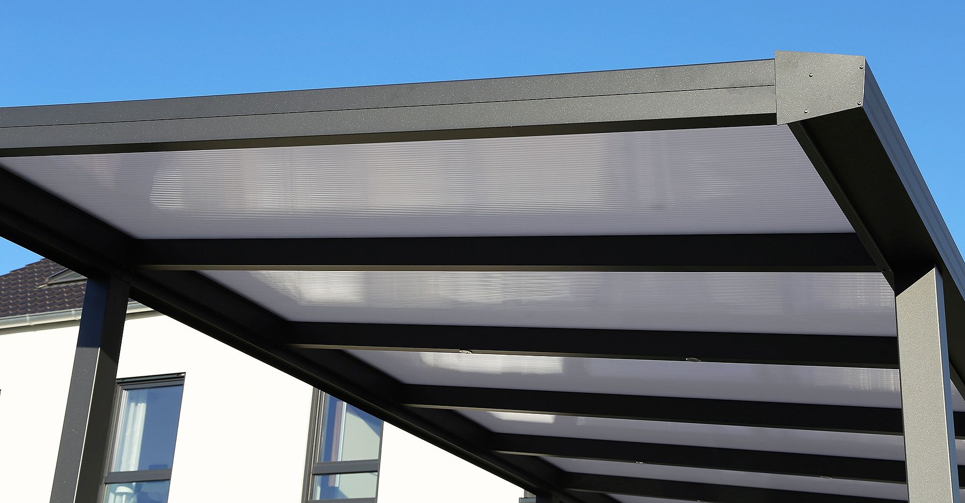 Ein schwarzes Carport mit einem Glasdach